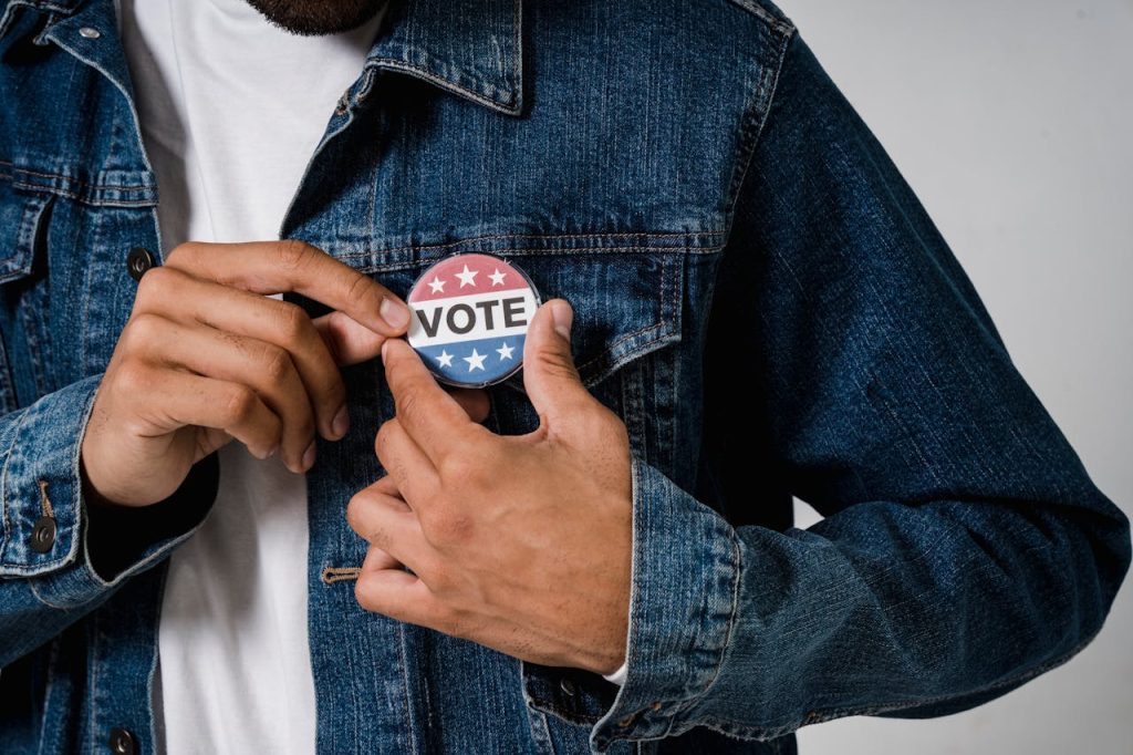 A person pinning a VOTE button on a denim jacket symbolizing civic engagement.