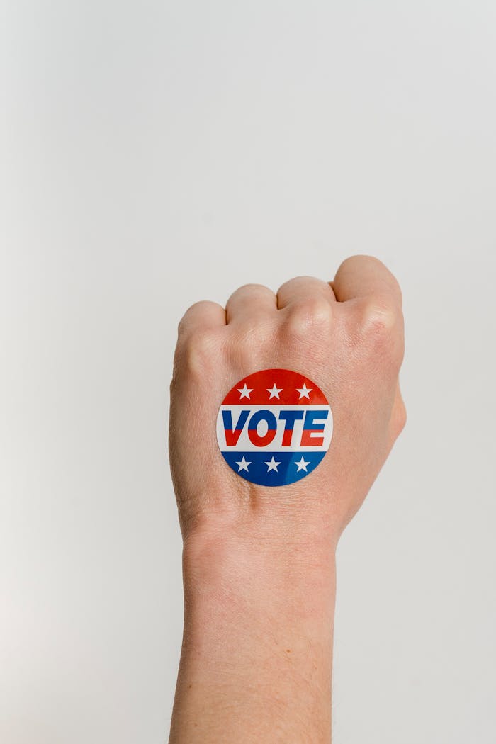 Close-up of a clenched fist with a patriotic Vote sticker symbolizing power and democracy.